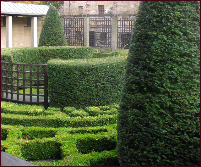 Perfectly trimmed hedges, upright evergreens, lattuce fence panels and brick walls provide formal sturcutre in the vertical plance while th wlow parterres [rovide the flooring in this old world courtyard. Photo: Evelyn Steinberg.